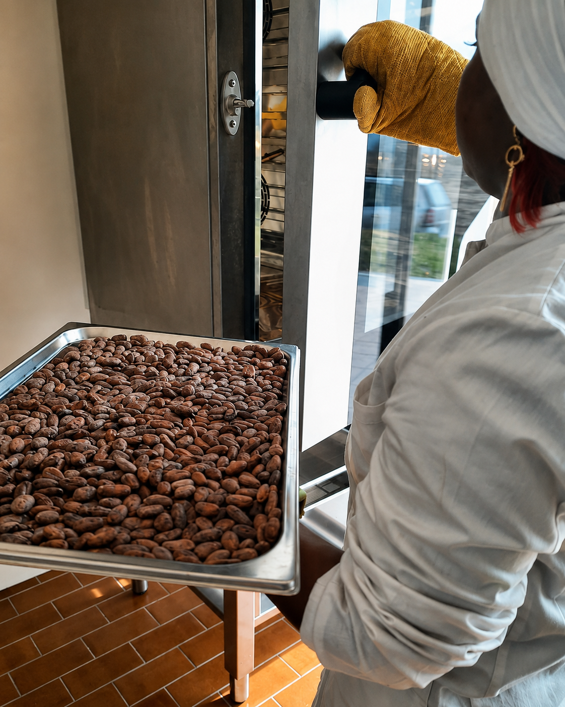 Operatrice che inforna una teglia di fave di cacao per la tostatura